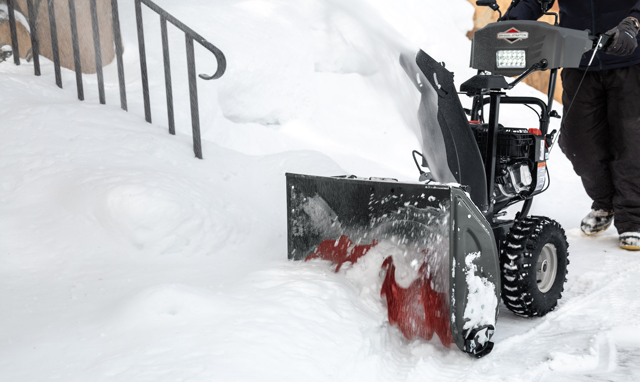 Person at a dealership looking at a snowblower with Briggs & Stratton engine.